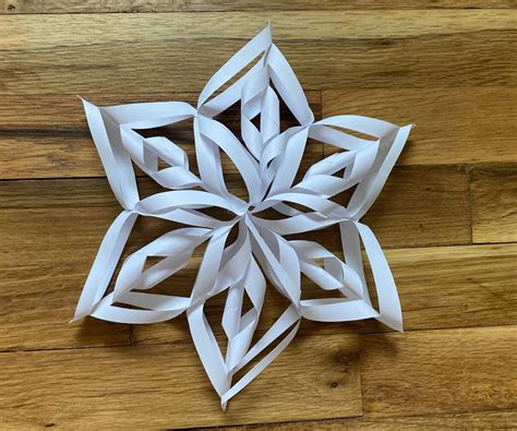 Once you have made a snowflake, unfold it. To turn it into an ornament, first lay it out flat on an ironing board. Then cover it with a thin white cloth ( I used a linen napkin) and press to flatten the cut doily. Next, simply punch a small hole into the top of the snowflake and attach an ornament hook.